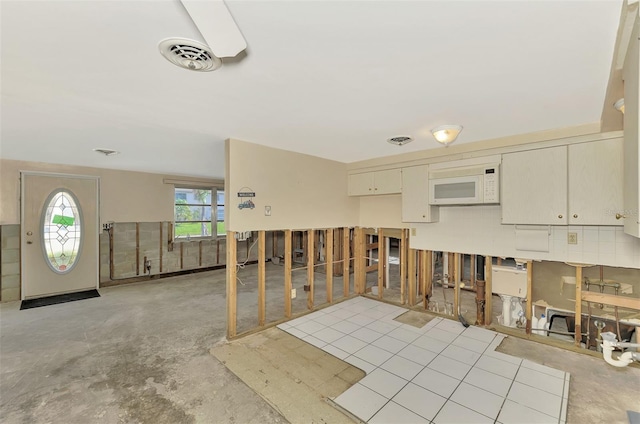 105 Crestview Dr, Englewood, FL 34223 - kitchen with white microwave, concrete floors, and cream cabinetry