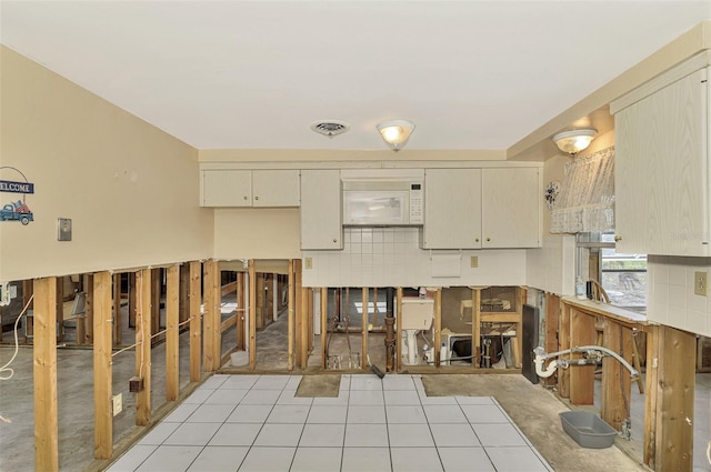 105 Crestview Dr, Englewood, FL 34223 - kitchen with light tile patterned flooring, cream cabinetry, and white microwave