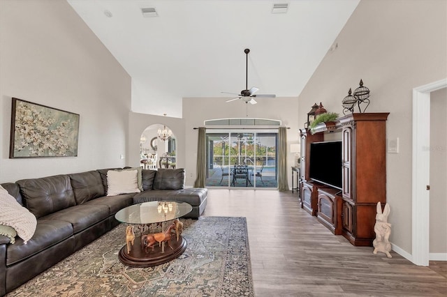 living room with high vaulted ceiling, light wood-type flooring, and ceiling fan with notable chandelier