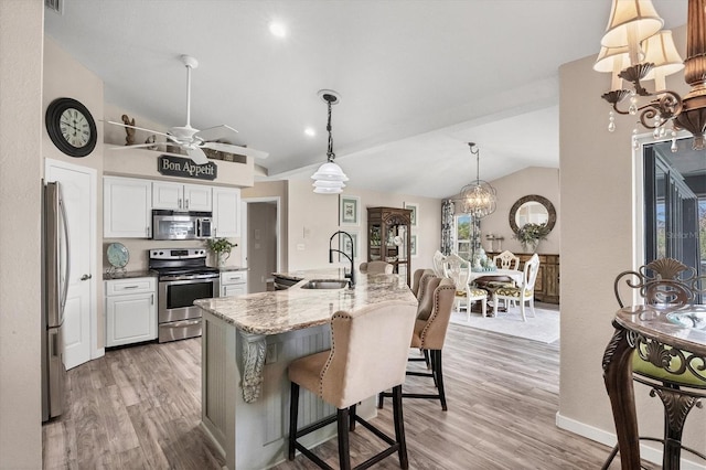 kitchen featuring sink, appliances with stainless steel finishes, lofted ceiling, white cabinets, and light wood-type flooring