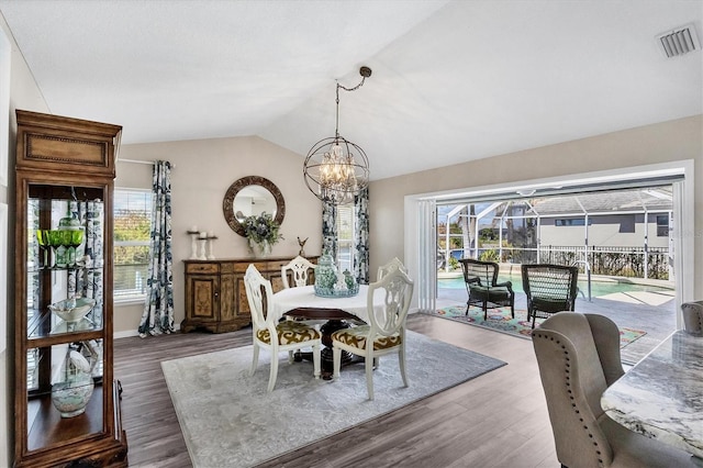 dining area with an inviting chandelier, vaulted ceiling, and dark hardwood / wood-style floors