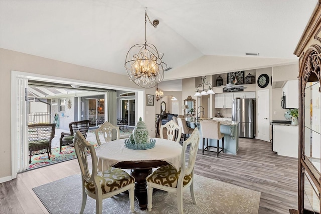 dining area featuring hardwood / wood-style floors, a chandelier, and vaulted ceiling