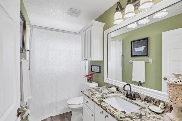 bathroom with vanity, hardwood / wood-style flooring, a textured ceiling, and toilet