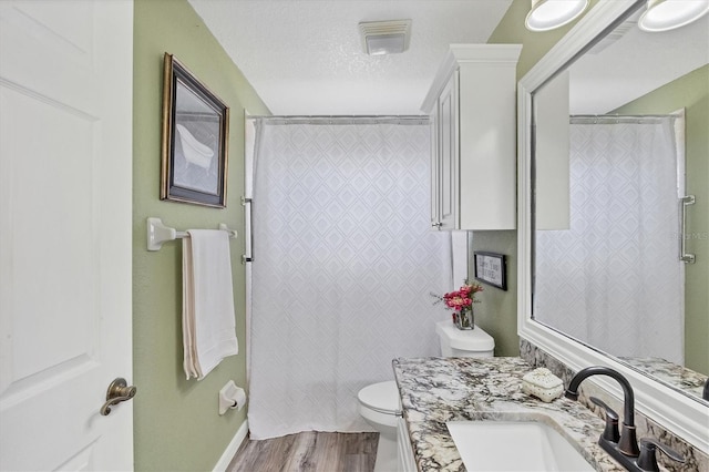 bathroom featuring toilet, vanity, a textured ceiling, and hardwood / wood-style flooring