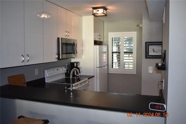 kitchen with white electric range oven, white cabinets, and fridge