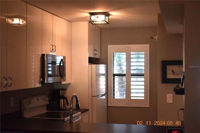 kitchen with white fridge, stove, and white cabinetry