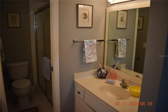 bathroom featuring hardwood / wood-style floors, vanity, toilet, and a shower with door