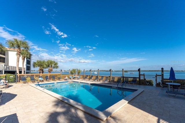 view of swimming pool with a patio area and a water view