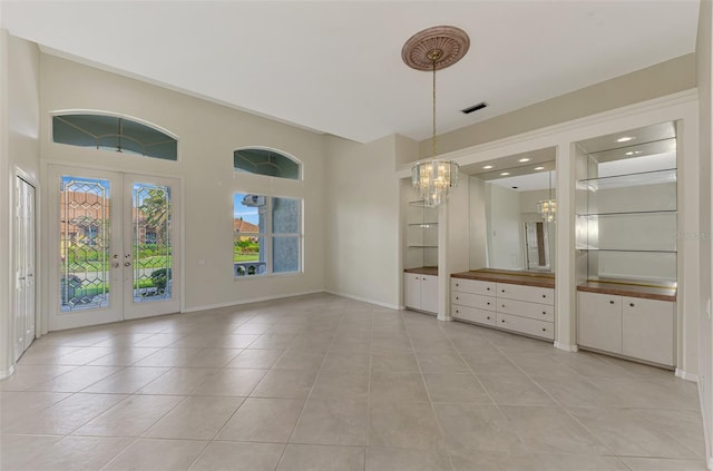 interior space with light tile patterned floors, an inviting chandelier, and french doors