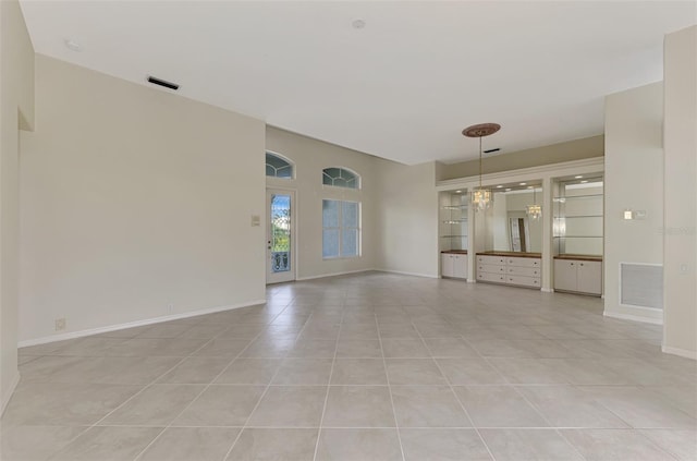 empty room with light tile patterned flooring and a notable chandelier