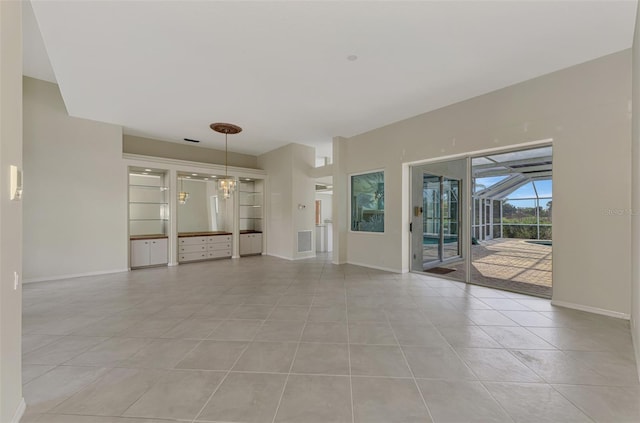 unfurnished living room with an inviting chandelier and light tile patterned floors