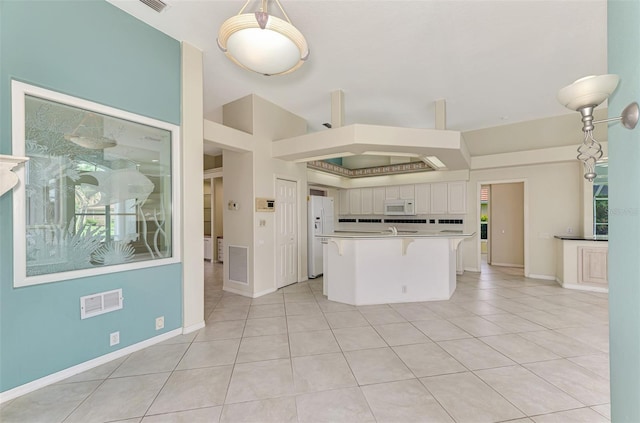 kitchen featuring pendant lighting, light tile patterned flooring, a breakfast bar, white cabinetry, and white appliances