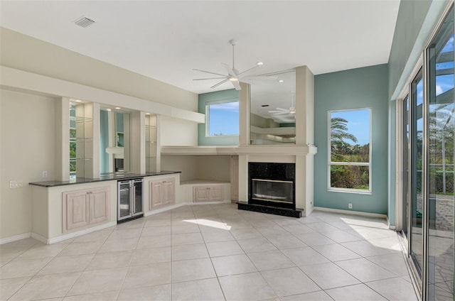 unfurnished living room featuring a fireplace, light tile patterned flooring, beverage cooler, and ceiling fan