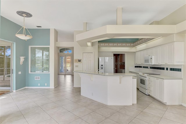 kitchen with white cabinetry, a kitchen island with sink, hanging light fixtures, and white appliances