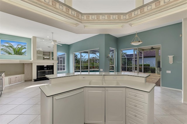 kitchen featuring white cabinets, a center island with sink, sink, and a raised ceiling