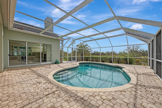 view of swimming pool featuring glass enclosure and a patio