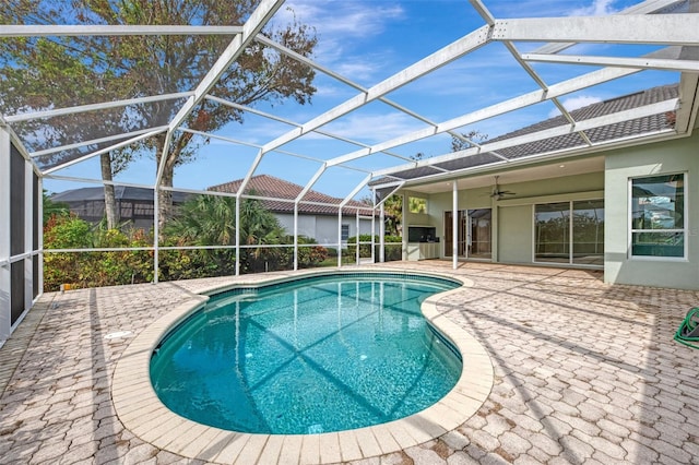 view of swimming pool featuring glass enclosure, a patio, and ceiling fan