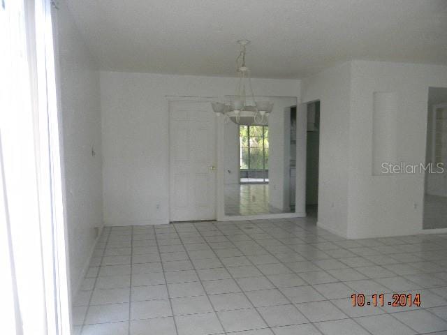 tiled empty room with a chandelier