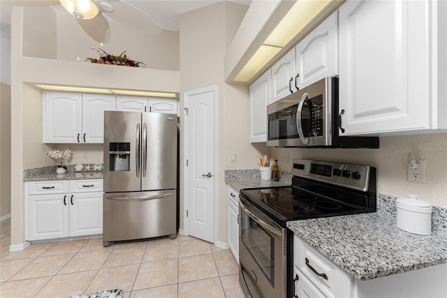 kitchen featuring light stone countertops, appliances with stainless steel finishes, ceiling fan, white cabinets, and light tile patterned floors