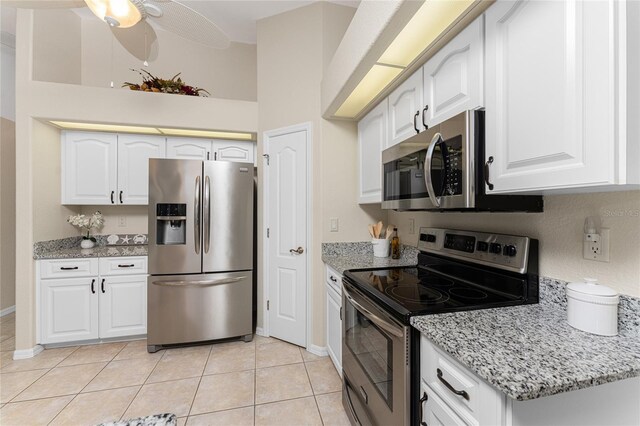 110 Abercrombie Ave, Englewood, FL 34223 - kitchen with stainless steel appliances, light tile patterned floors, light stone countertops, white cabinets, and baseboards