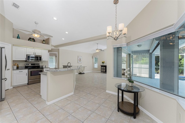 kitchen with white cabinets, light tile patterned floors, appliances with stainless steel finishes, dark stone countertops, and pendant lighting