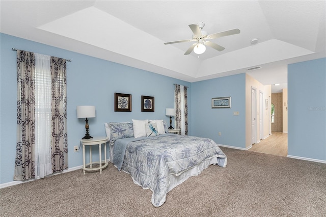 carpeted bedroom with ensuite bathroom, a tray ceiling, and ceiling fan