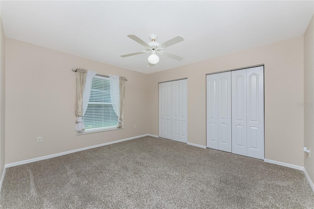 unfurnished bedroom featuring ceiling fan, carpet flooring, and two closets