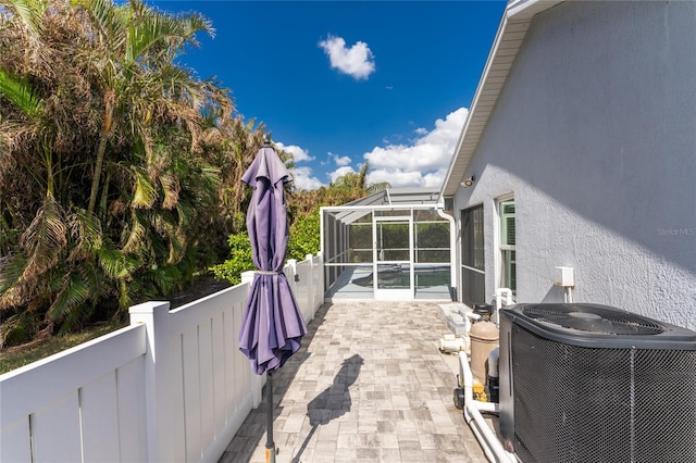 view of patio / terrace with central air condition unit, a swimming pool, and glass enclosure