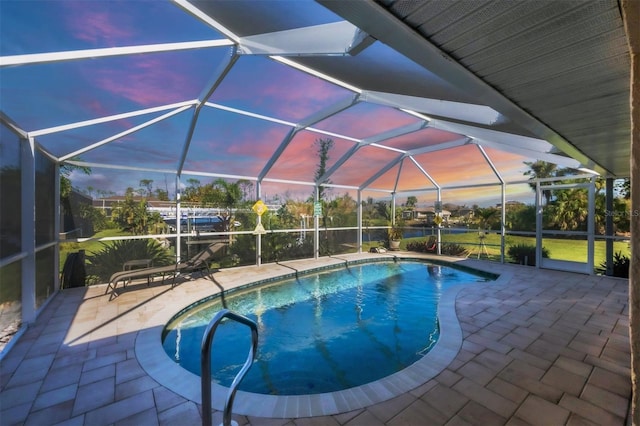 pool at dusk featuring glass enclosure and a patio area