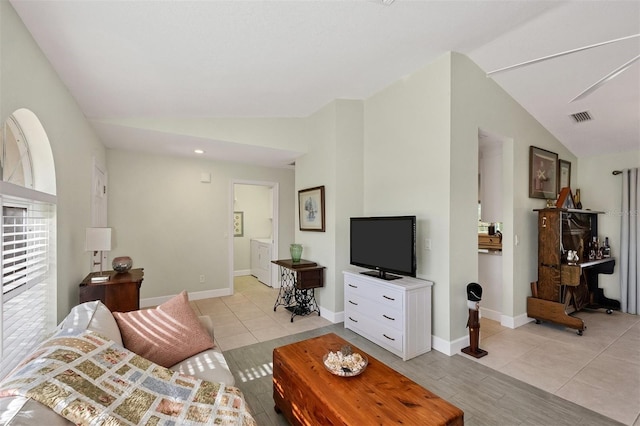 tiled living room with lofted ceiling and independent washer and dryer