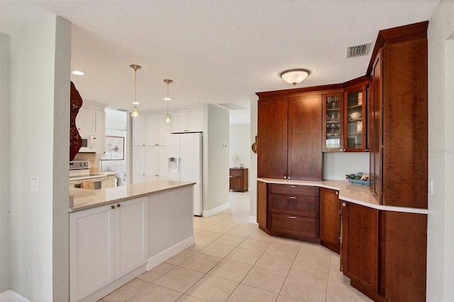 kitchen with white appliances, light tile patterned floors, a textured ceiling, and hanging light fixtures