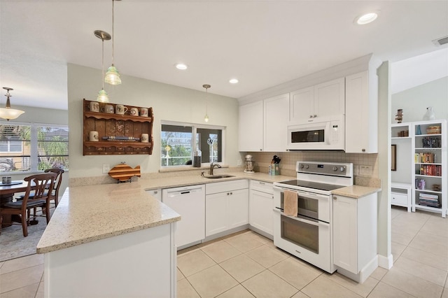 kitchen featuring white appliances, white cabinetry, hanging light fixtures, sink, and kitchen peninsula