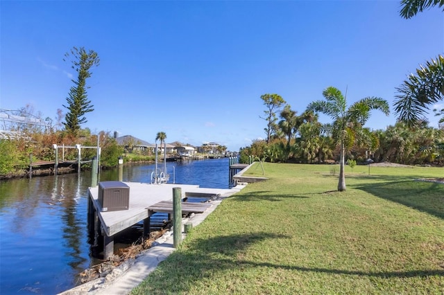 view of dock with a lawn and a water view