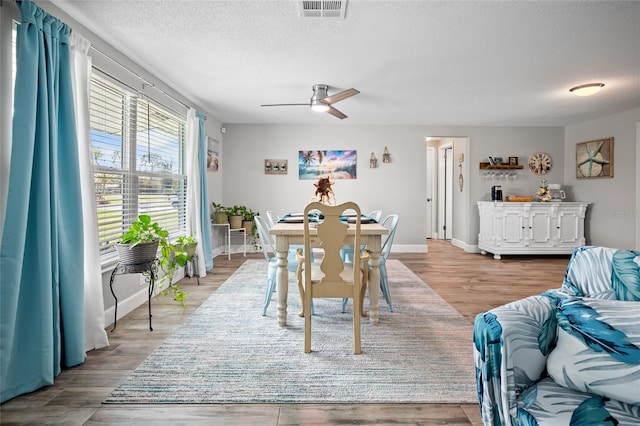 dining room with a textured ceiling, ceiling fan, and light hardwood / wood-style flooring