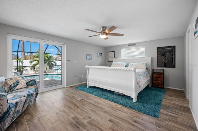 bedroom with access to outside, multiple windows, wood-type flooring, and ceiling fan