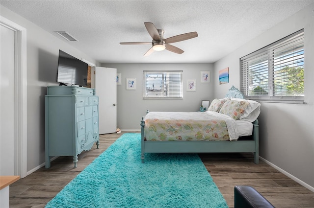 bedroom featuring a textured ceiling, wood-type flooring, multiple windows, and ceiling fan