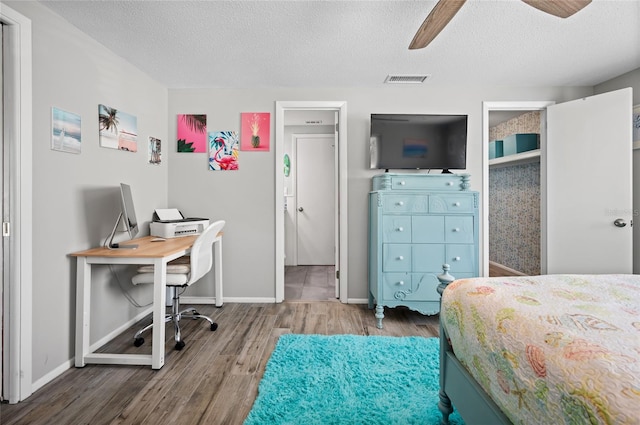 bedroom with hardwood / wood-style flooring, a textured ceiling, and ceiling fan