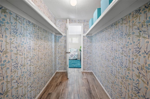 corridor with a textured ceiling and hardwood / wood-style flooring