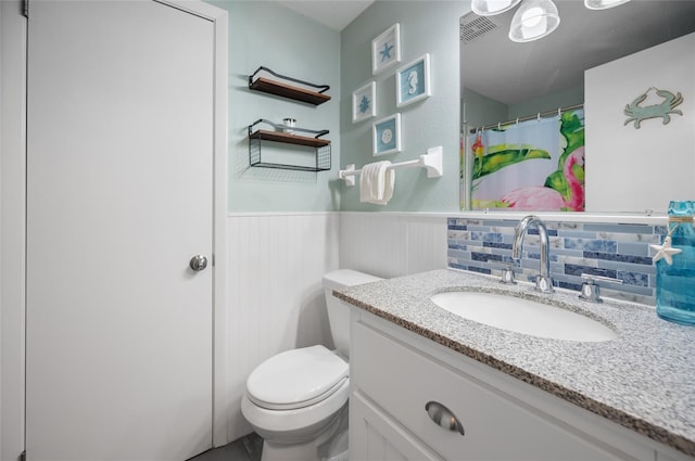 bathroom featuring toilet, vanity, and decorative backsplash