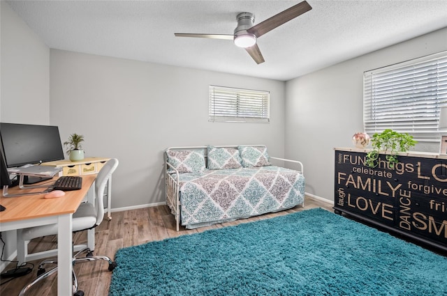 bedroom with a textured ceiling, hardwood / wood-style floors, and ceiling fan