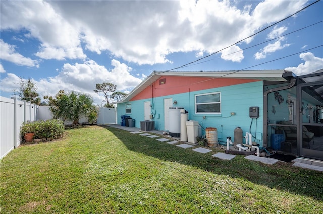 back of house with central AC unit and a lawn