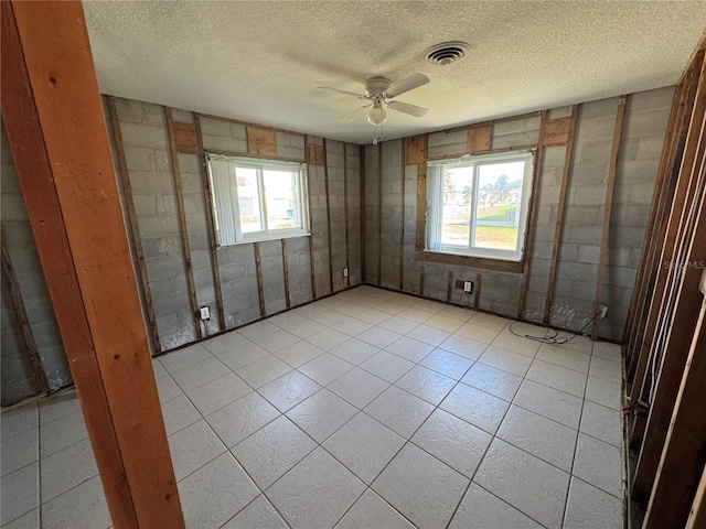 tiled spare room featuring ceiling fan, a healthy amount of sunlight, and a textured ceiling