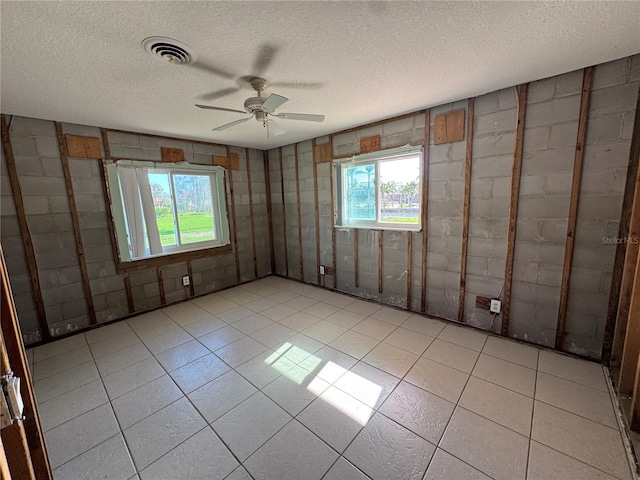 unfurnished room featuring a wealth of natural light, a textured ceiling, ceiling fan, and light tile patterned floors