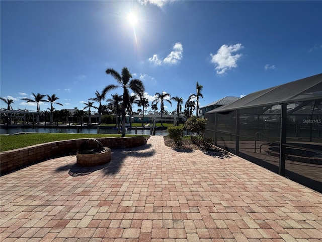 view of patio featuring glass enclosure and a water view