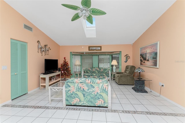 tiled living room featuring lofted ceiling with skylight and ceiling fan