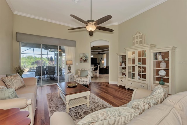 living room with dark wood-type flooring, ceiling fan, and crown molding