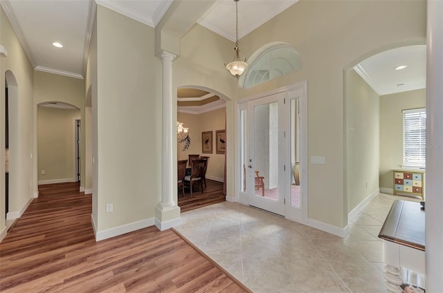 entryway with ornamental molding, ornate columns, and light tile patterned flooring