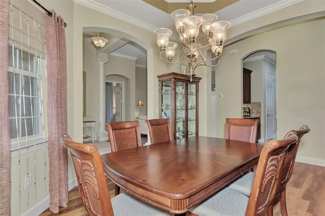 dining area with a notable chandelier, ornamental molding, and light wood-type flooring