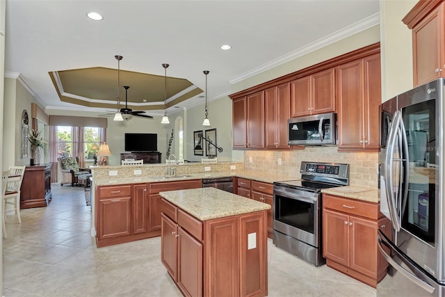 kitchen with sink, decorative light fixtures, appliances with stainless steel finishes, a tray ceiling, and kitchen peninsula