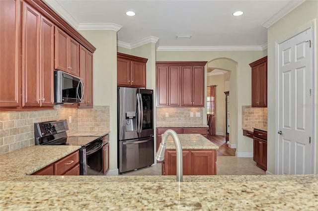 kitchen with a kitchen island, appliances with stainless steel finishes, decorative backsplash, ornamental molding, and light stone counters